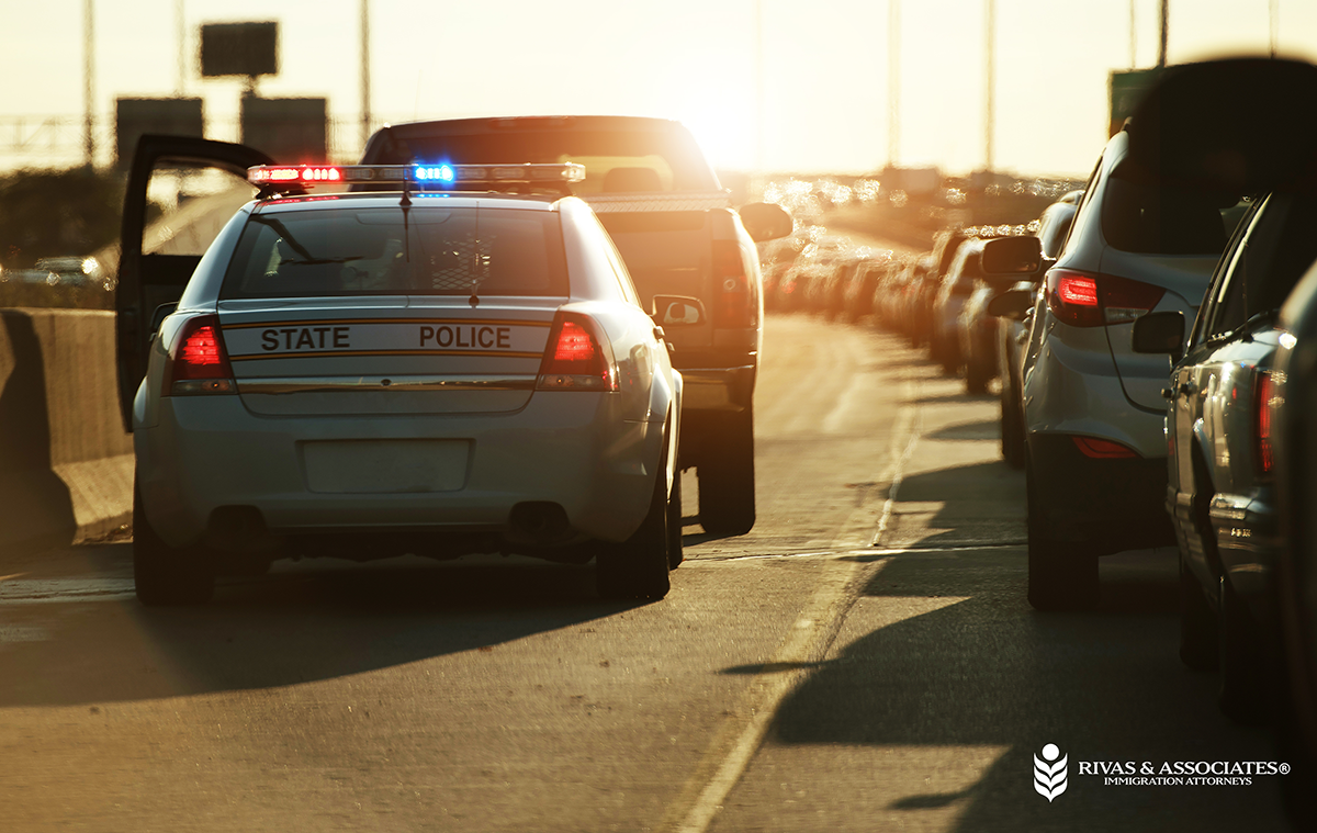 State police car with lights on during a highway traffic stop. Know your rights during police and ICE stops. Rivas & Associates.